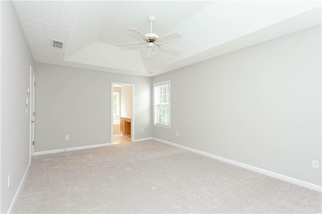 carpeted empty room with ceiling fan and a tray ceiling