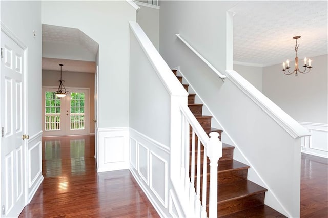 staircase featuring a chandelier, dark wood-type flooring, a textured ceiling, and french doors