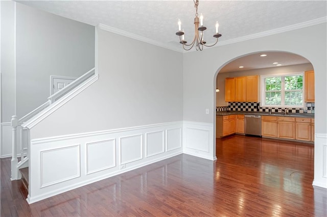 empty room featuring dark hardwood / wood-style flooring, an inviting chandelier, and crown molding