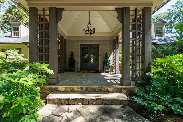 doorway to property with brick siding, a porch, and french doors