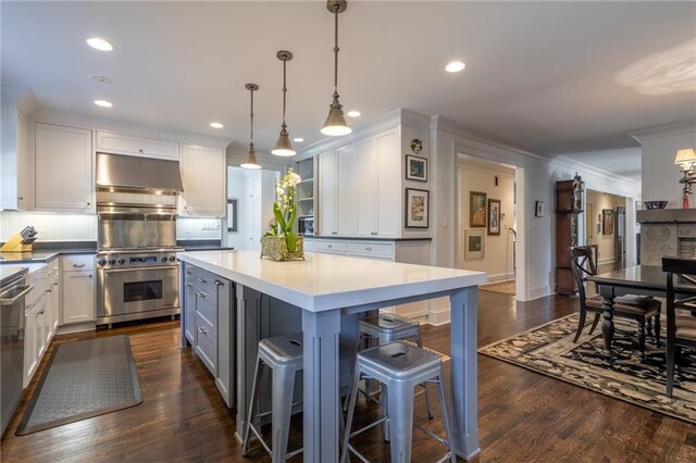 kitchen featuring a kitchen island, appliances with stainless steel finishes, a breakfast bar, under cabinet range hood, and white cabinetry