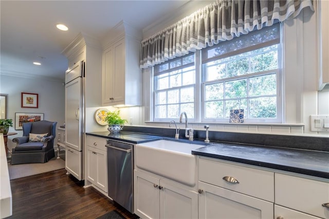 kitchen featuring built in fridge, dark countertops, a sink, and stainless steel dishwasher