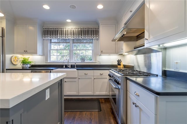 kitchen featuring dark wood-style floors, stainless steel range, white cabinets, a sink, and under cabinet range hood