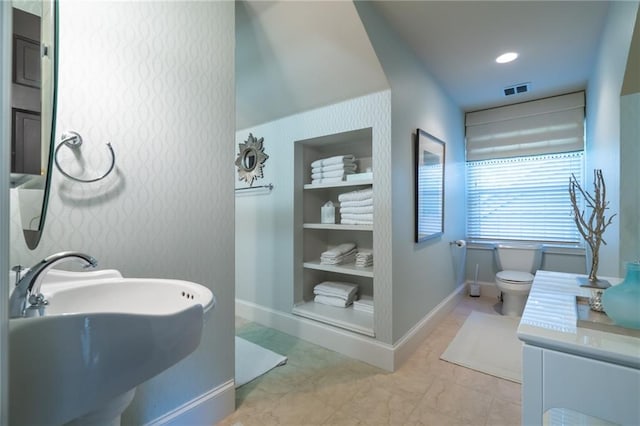 bathroom featuring baseboards, built in shelves, visible vents, and a sink