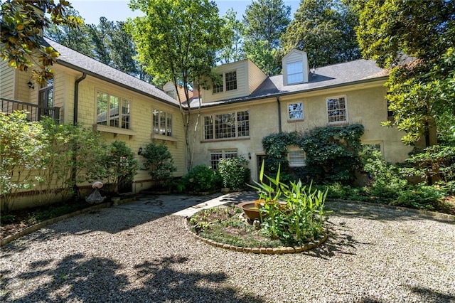 rear view of house featuring stucco siding