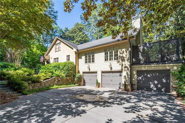 view of front of property with concrete driveway, a chimney, and an attached garage