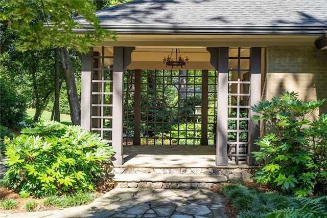 doorway to property with roof with shingles and brick siding