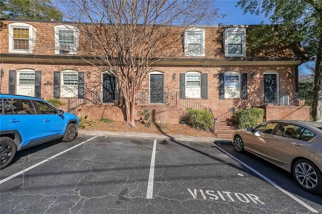 view of property featuring uncovered parking and brick siding