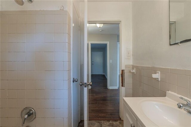 bathroom featuring vanity, tiled shower / bath combo, and tile walls