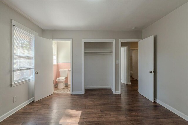 unfurnished bedroom featuring ensuite bath, a closet, and dark hardwood / wood-style floors