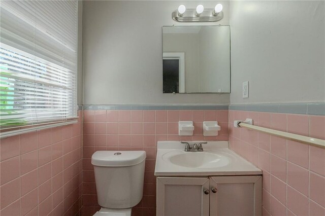 bathroom with vanity, tile walls, and toilet