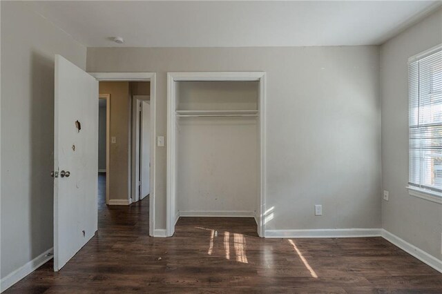 unfurnished bedroom with dark wood-type flooring and a closet