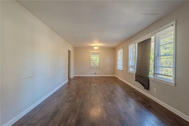 spare room featuring dark hardwood / wood-style flooring and a wealth of natural light