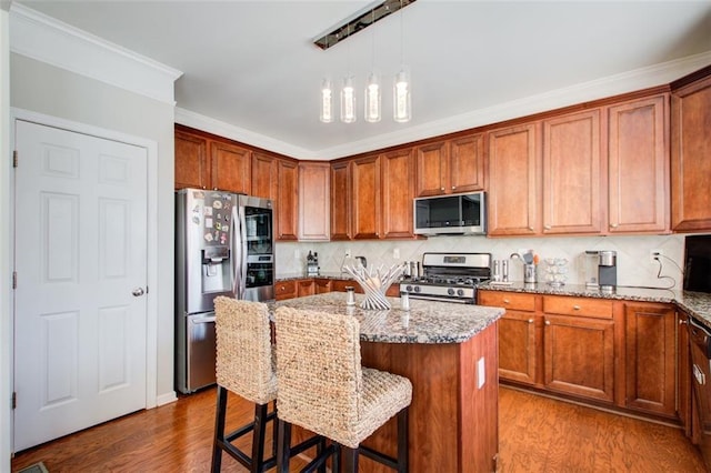 kitchen with a breakfast bar area, appliances with stainless steel finishes, backsplash, light stone counters, and wood-type flooring