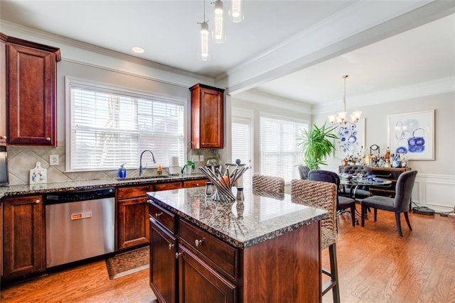 kitchen with a kitchen island, pendant lighting, sink, dark stone countertops, and stainless steel dishwasher