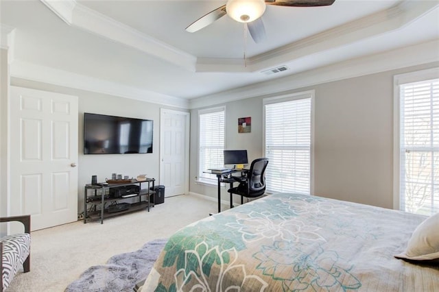 bedroom featuring ornamental molding, light colored carpet, ceiling fan, and a tray ceiling