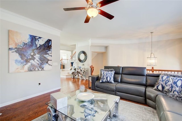 living room featuring hardwood / wood-style flooring, ceiling fan with notable chandelier, and ornamental molding