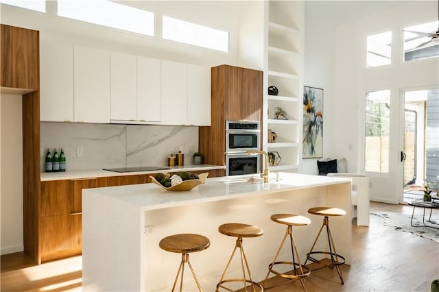 kitchen with white cabinetry, double oven, a wealth of natural light, and a breakfast bar area