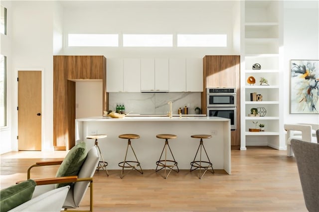 kitchen with kitchen peninsula, white cabinets, a breakfast bar area, and double oven