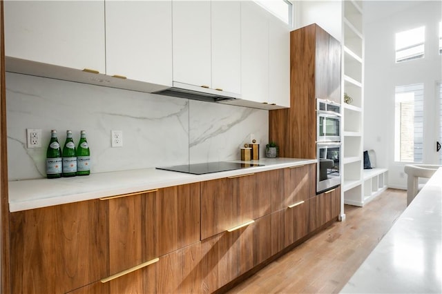 kitchen with white cabinetry, black electric stovetop, light hardwood / wood-style flooring, and tasteful backsplash