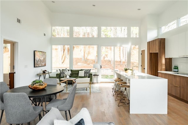 dining area featuring a high ceiling, sink, and light wood-type flooring