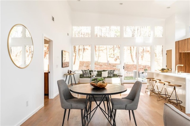 dining space featuring light hardwood / wood-style floors and a high ceiling