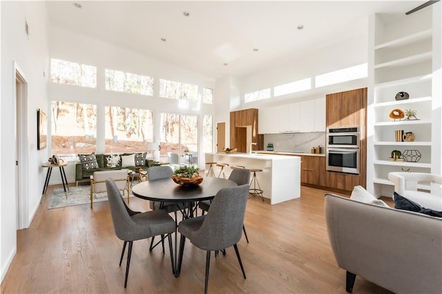 dining space with light hardwood / wood-style flooring and a towering ceiling