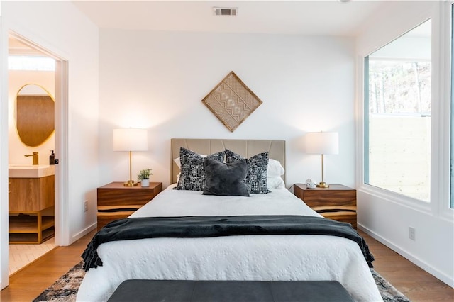 bedroom featuring sink, light wood-type flooring, and connected bathroom