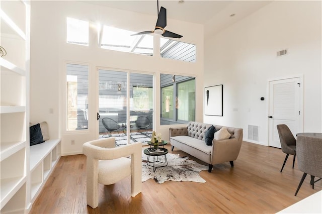 living room with wood-type flooring, a towering ceiling, and ceiling fan