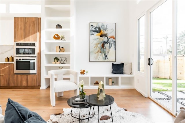 living area featuring built in features and light hardwood / wood-style flooring