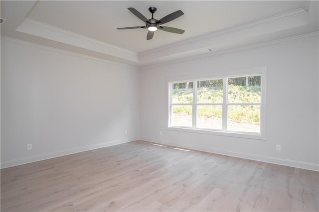 spare room with ceiling fan, light hardwood / wood-style floors, crown molding, and a tray ceiling