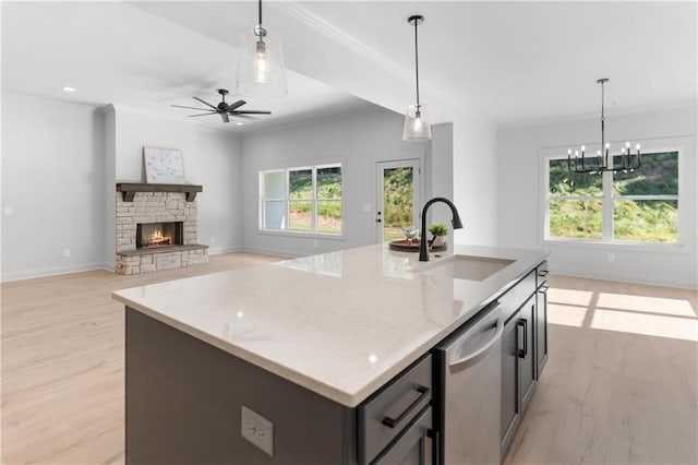 kitchen with light stone countertops, sink, an island with sink, and light hardwood / wood-style floors