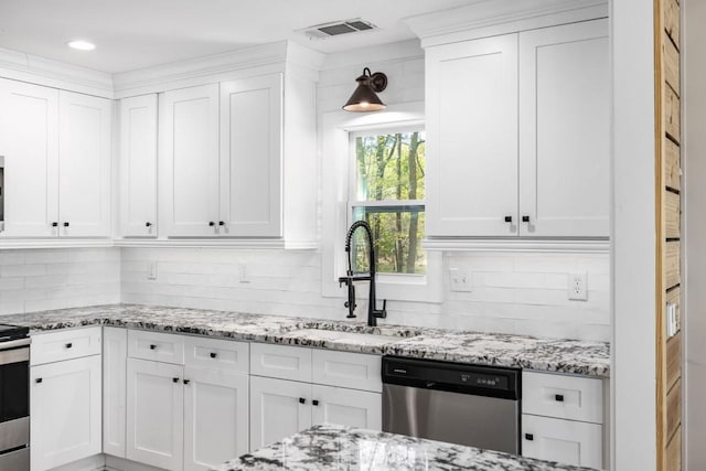 kitchen featuring stainless steel appliances, a sink, white cabinetry, and backsplash