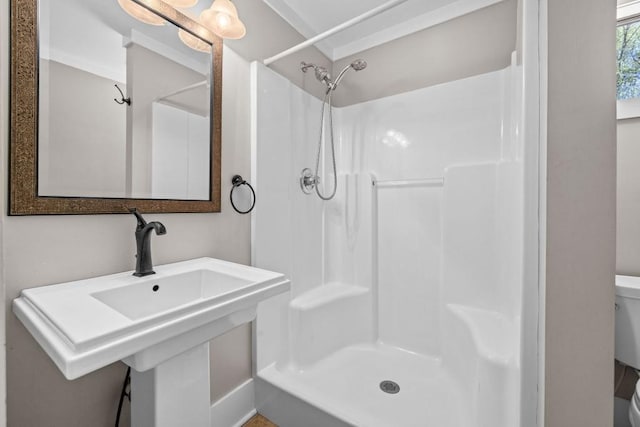 bathroom featuring toilet, a stall shower, and a sink