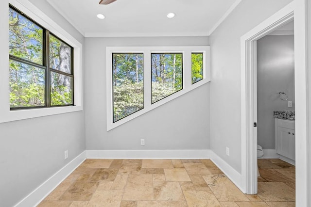 spare room featuring plenty of natural light, stone tile flooring, baseboards, ornamental molding, and recessed lighting