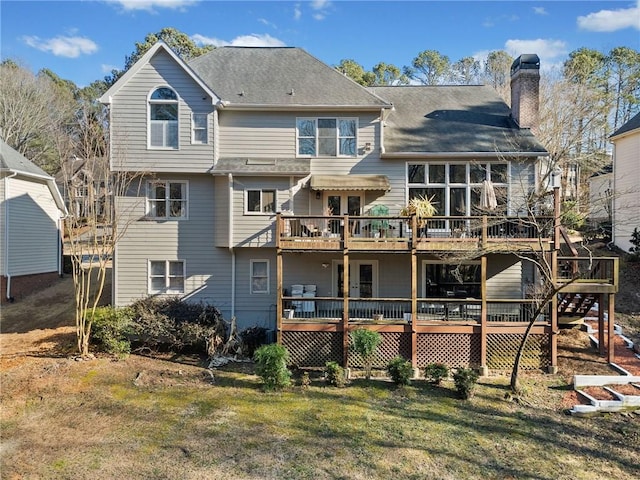 back of property with a deck, a chimney, and a lawn