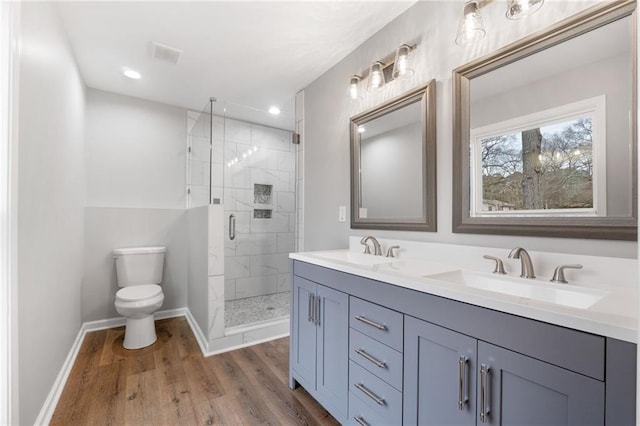 bathroom featuring vanity, hardwood / wood-style floors, a shower with door, and toilet