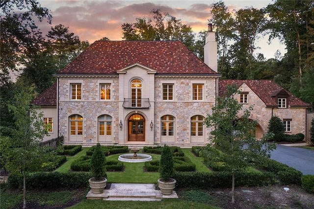 view of front of home featuring a balcony and a yard