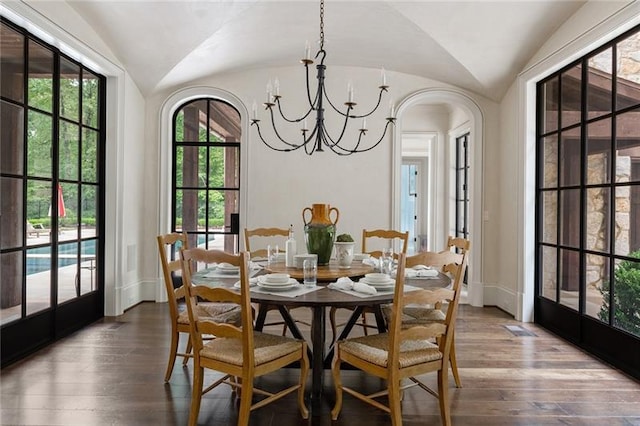 dining space with plenty of natural light, vaulted ceiling, hardwood / wood-style floors, and a chandelier