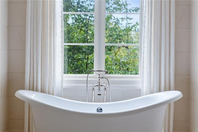 bathroom featuring a bath to relax in and tile walls