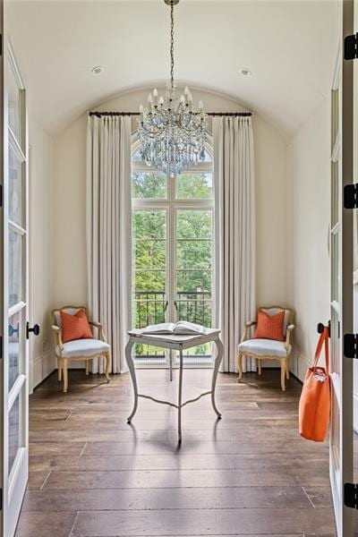 sitting room featuring wood-type flooring, vaulted ceiling, and an inviting chandelier