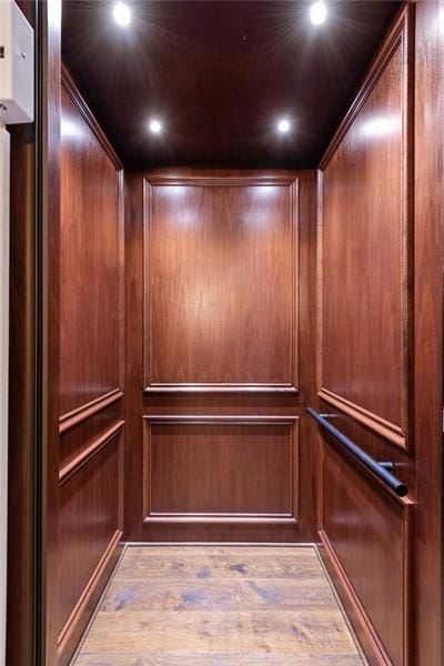 interior details with wood walls, hardwood / wood-style floors, and elevator