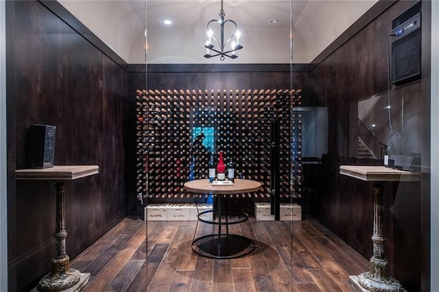 wine room featuring an inviting chandelier, vaulted ceiling, and dark wood-type flooring