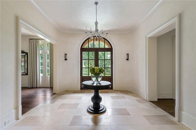 tiled foyer featuring an inviting chandelier, crown molding, and french doors