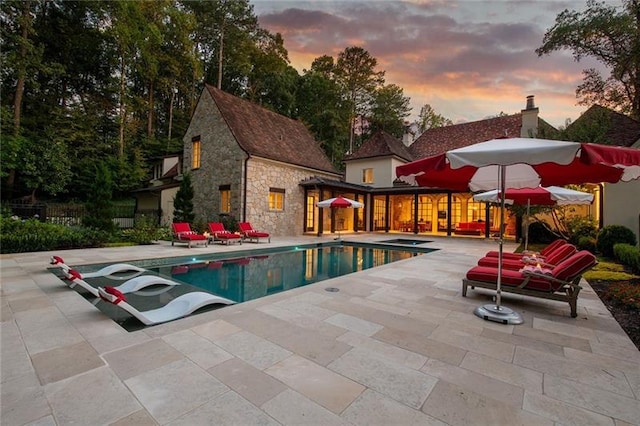 pool at dusk with a patio area