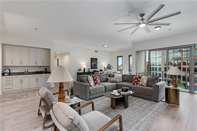 living room with sink, light hardwood / wood-style floors, and ceiling fan