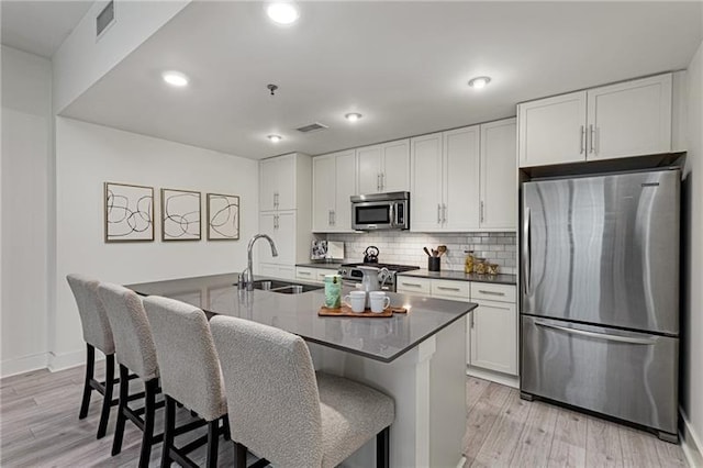 kitchen with a breakfast bar, white cabinetry, sink, a kitchen island with sink, and stainless steel appliances