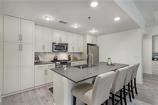 kitchen featuring white cabinetry, sink, an island with sink, and appliances with stainless steel finishes