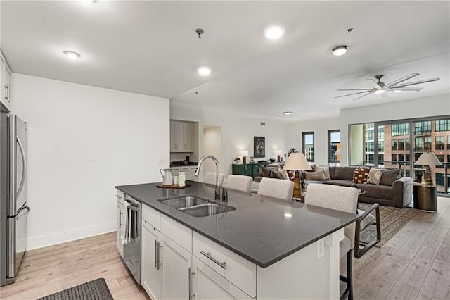 kitchen with sink, a breakfast bar, white cabinetry, a kitchen island with sink, and stainless steel appliances