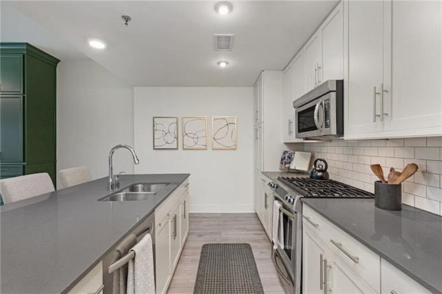 kitchen featuring sink, white cabinetry, dark stone countertops, appliances with stainless steel finishes, and backsplash